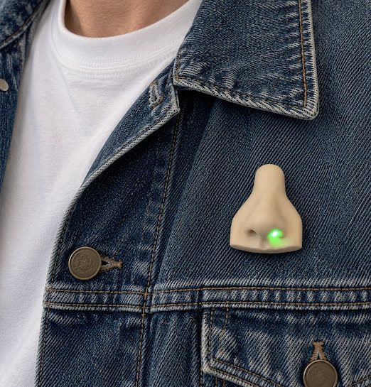Concept image of a skin-coloured nose-shaped badge on a denim jacket lapel, one nostril glowing green